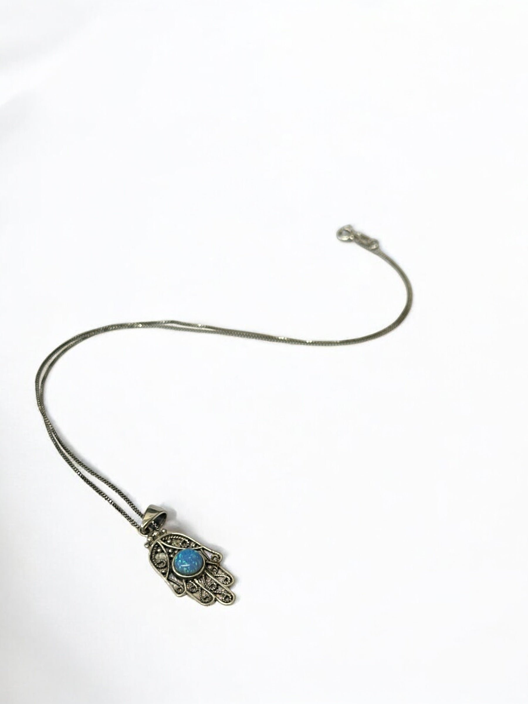 Close-up of natural opal stone set in hamsa hand pendant