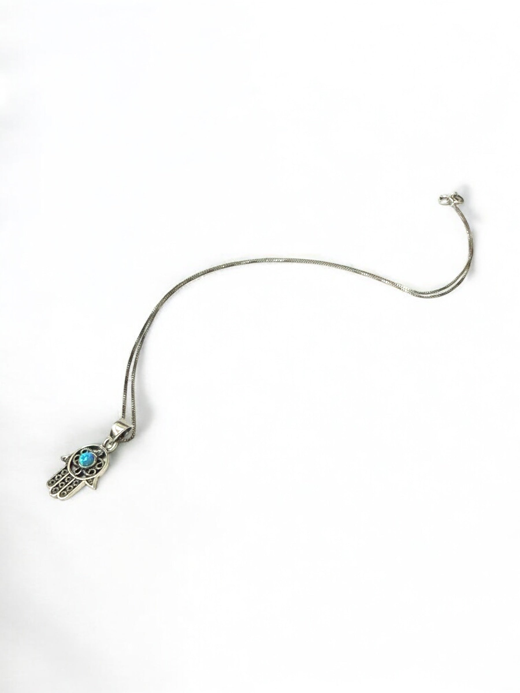 Close-up of opal-set hamsa pendant detail